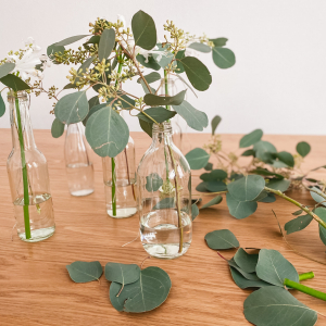 Befülle die Glasflaschen mit ein wenig Wasser befüllen und stecke die bereits vorgeschnittenen Blumen hinein!