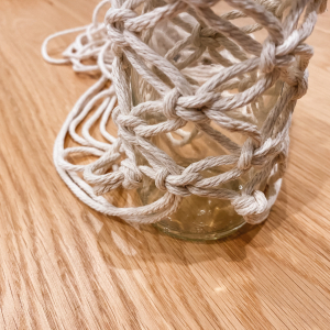 Mit dem versetzten Knüpfen des Musters machst du weiter, bis das Muster ans untere Ende der Flasche reicht. 